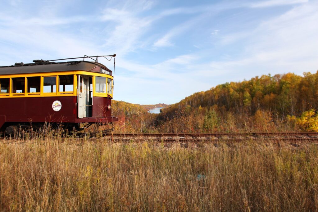 The vintage trolley at Minnesota Discovery Center in Chisholm, MN rides along a mine pit in the fall. 