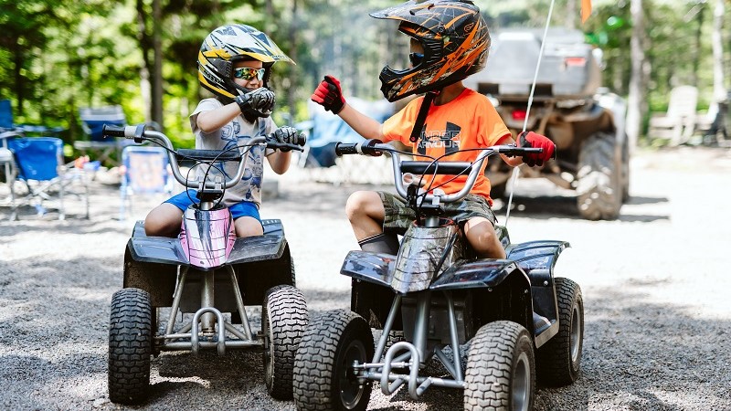 Two boys on ATVs pause to do a fist bump.