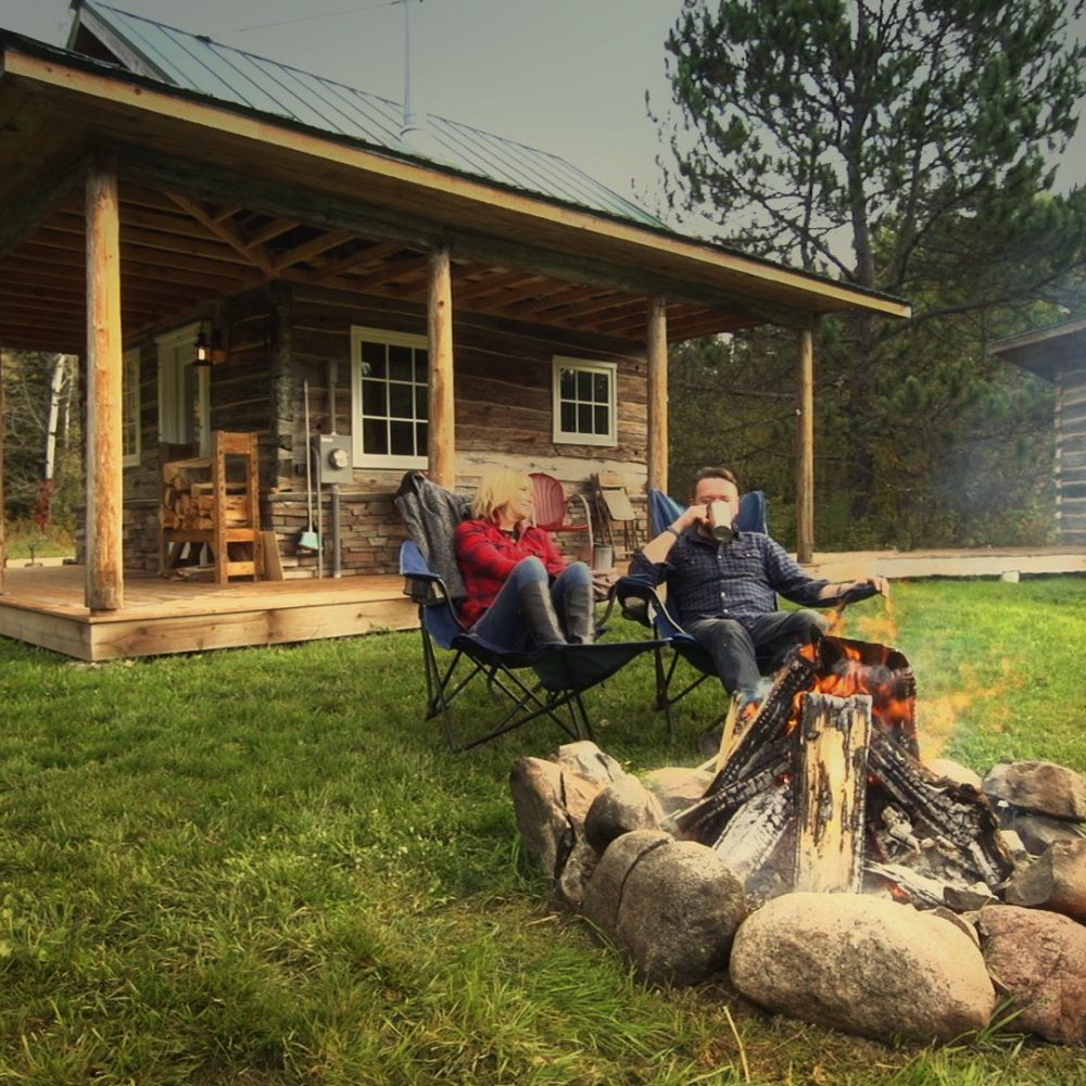 A couple sits by a campfire at Green Gate Guest Houses in Biwabik, MN