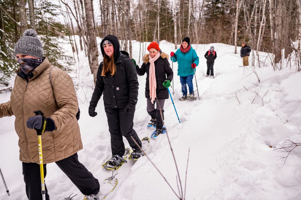 A group of people snowshoes on a trail at Minnesota Discovery Center in northern Minnesota