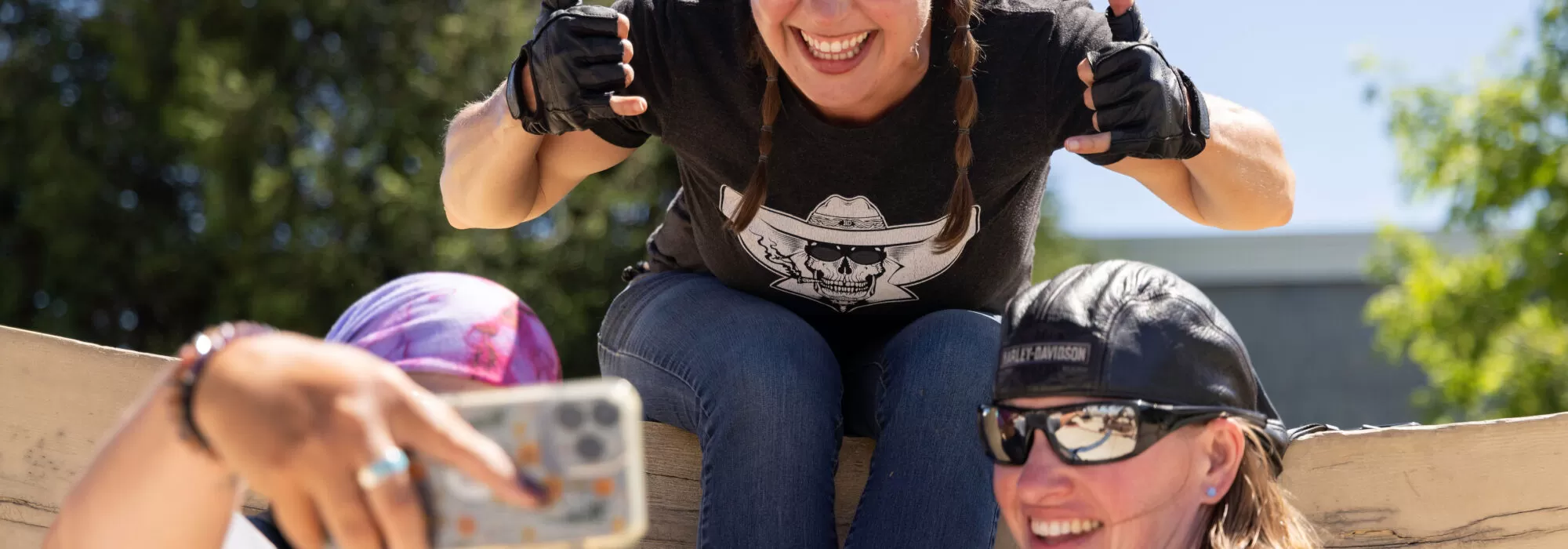 three women pose for a selfie on a sunny day