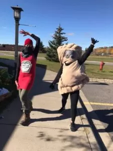 Two women are wearing costumes, one is a pasty and the other is a bottle of ketchup
