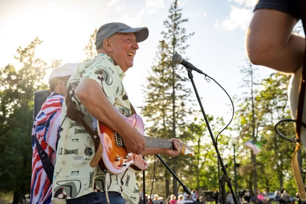 A man plays guitar at an outdoor music event in Virginia, Minnesota