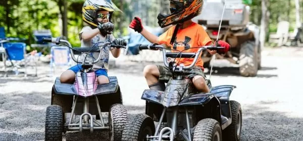 Two boys on ATVs pause to do a fist bump.