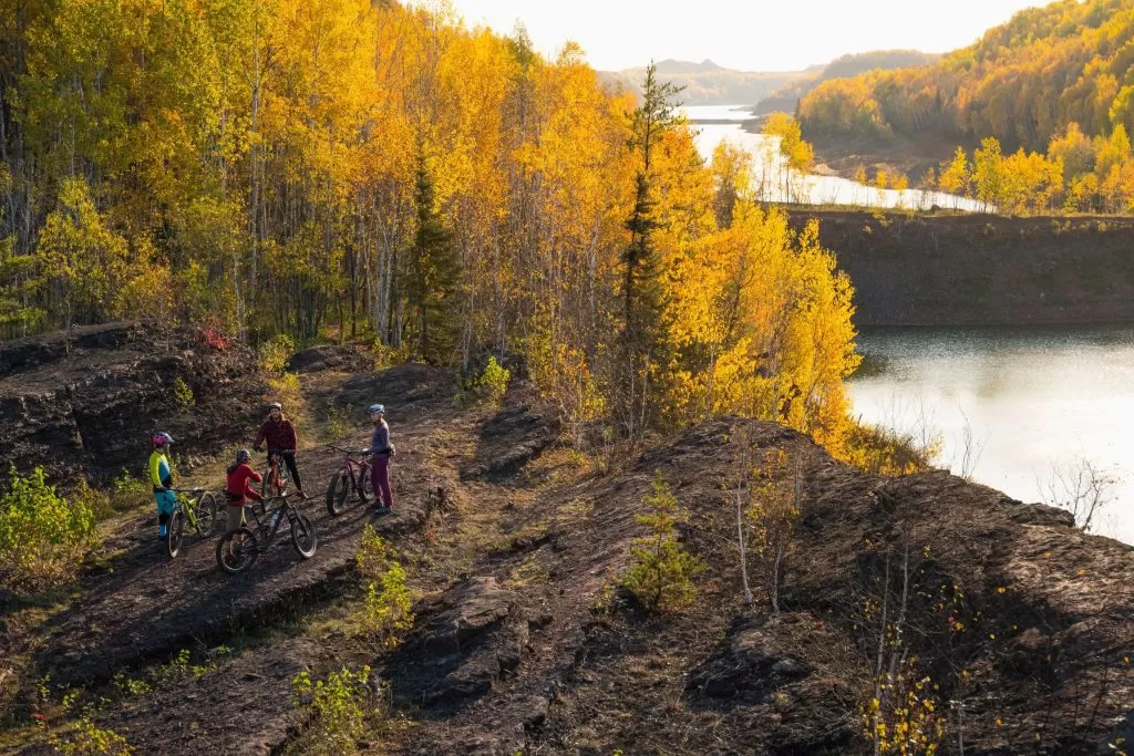 Riders pause on a cliff overlooking a lake at Redhead Mountain Bike Park in Chisholm, MN 