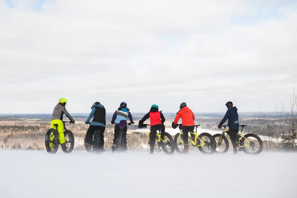 Cyclists stand near fat tire bikes in winter, overlooking the Superior National Forest in northern Minnesota