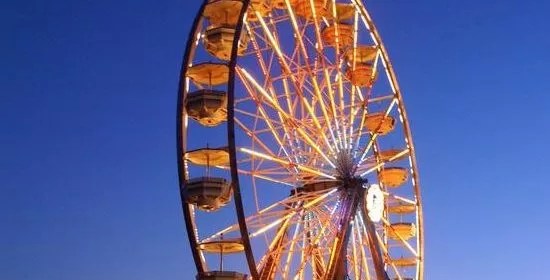 A ferris wheel at the Northern St Louis County Fair in Minnesota shines against a blue sky.