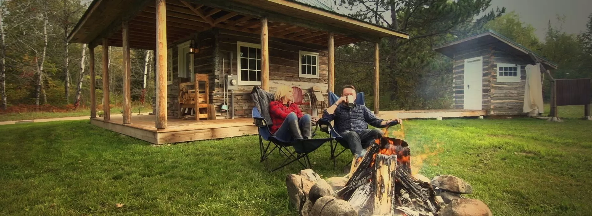A couple sits by a campfire at Green Gate Guest Houses in Biwabik, MN
