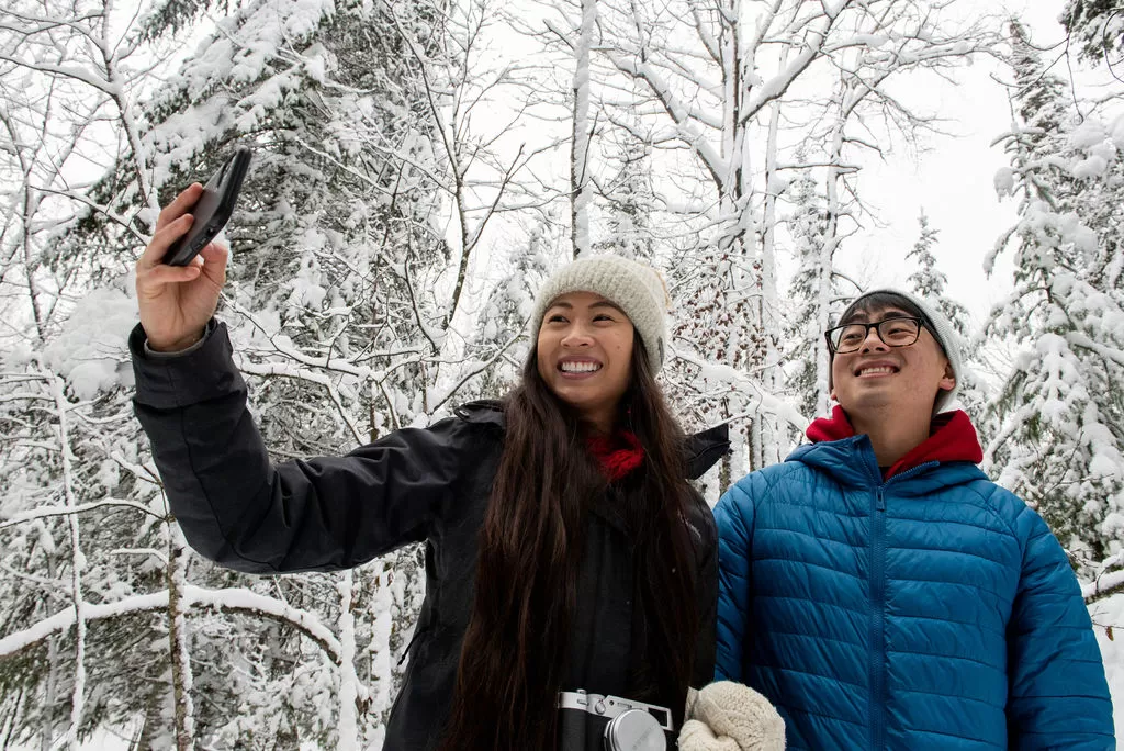 A couple smiles for a selfie in the winter on a snowshoe trail near the Sax Zim Bog welcome center in northern Minnesota.