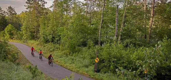 Three cyclists bike along the paved Mesabi Trail in northern Minnesota.